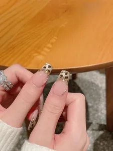 Detail of handmade press-on nails with leopard print, pearls, and rhinestones