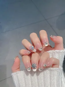 Close-up of almond handmade press-on nails with silver glitter, pearls and rhinestones