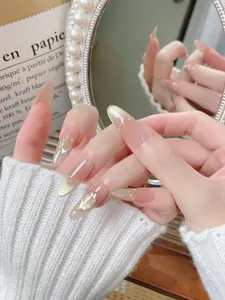 Macro detail of almond press-on nails with nude cat-eye shimmer, pearls and 3D butterfly
