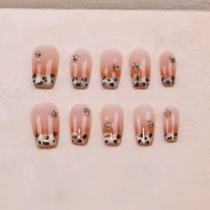 Faux ongles ombrés léopard caramel avec paillettes et strass sur support beige