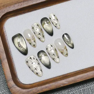 Faux ongles stiletto faits main avec œil de chat doré, paillettes et détails en perles