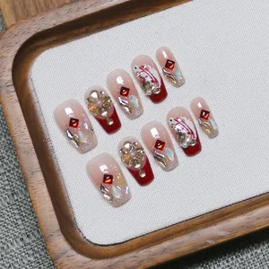Handmade red and nude gradient press-on nails with luxury rhinestones and pearl details