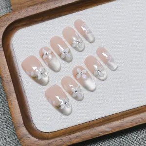 Handmade cat-eye press-on nails in oval shape with 3D white floral decor and pink base