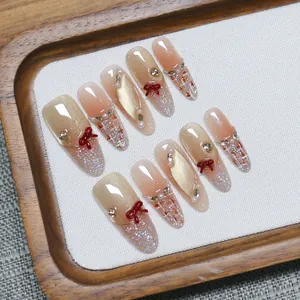 Handmade press-on nails with champagne cat-eye effect and red bow accents