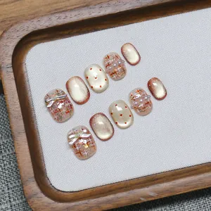 Handmade pink cat-eye press-on nails with tweed pattern and pearl bow accents