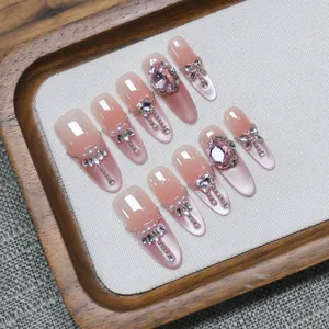 Pink cat eye press-on nails with 3D heart gems and pearl chains for a luxury look