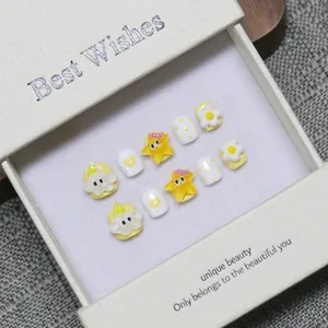 Handmade yellow and white press-on nails for kids featuring cute stars and flower art