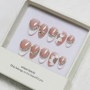 Handmade almond press-on nails with 3D floral accents and French tips in a gift box