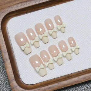 French tip press-on nails in nude pink with 3D cream bows and long coffin shape nails