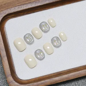 Short handmade press-on nails in cream white with aurora glitter and silver border details