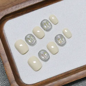 Handmade short press-on nails in cream and shimmering silver glitter with metallic beads