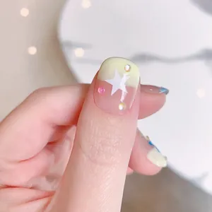 Handmade light yellow press-on nails with white stars and delicate rhinestone decorations