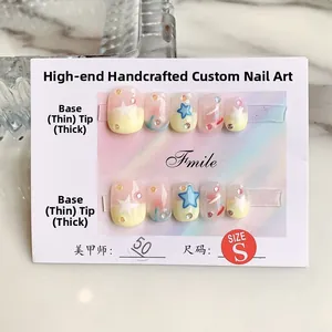 Detailed view of handmade press-on nails featuring yellow-pink gradient and blue star art