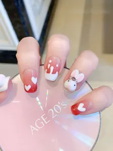 Détail de faux ongles faits main avec dégradé rouge, lapin 3D et motifs de cœurs