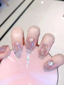 Detalle de uñas postizas Aurora rosa con lentejuelas holográficas y diamantes de imitación