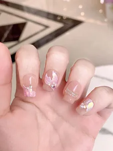 Detail of handmade press-on nails with mermaid shell texture, pearls and gold chain decor