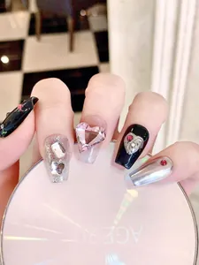 Detail of luxury press-on nails featuring pink heart gems and sparkling rhinestones