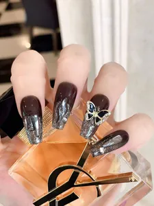 Dettaglio di unghie finte coffin marroni con glitter argento e decorazione a farfalla 3D