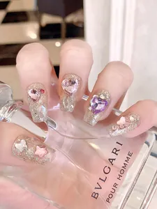 Macro detail of coffin press-on nails with champagne glitter and 3D rhinestone hearts