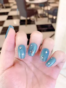 Detail of blue cat eye press-on nails with silver star motifs and tiny rhinestones