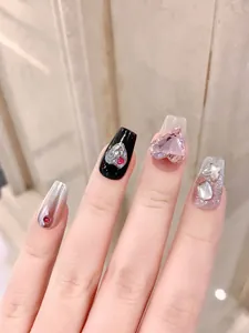 Macro detail of press-on nails featuring pink 3D gems, red rhinestones and silver chrome finish