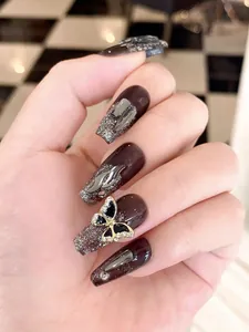 Dettagli unghie finte lunghe marroni con fiamme argento e farfalla 3D con strass