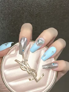 Detail of long coffin nails featuring silver chrome, blue tones, and a large heart crystal