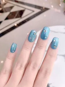 Detail of blue cat-eye press-on nails with silver star patterns and sparkling rhinestones