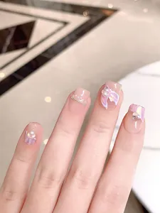 Macro shot of handmade press-on nails with mermaid style 3D butterfly and pearl accents
