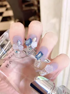 Detalle de uñas postizas con degradado azul, rosas 3D y cristales brillantes
