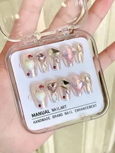 Gros plan d'ongles faits main cœur mocha avec finition aurora et bijoux 3D brillants