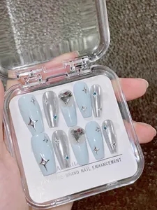 Detail of silver and blue handmade press-on nails with heart charms and starburst accents