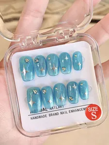 Close-up of handmade blue cat-eye press-on nails with silver stars and glitter