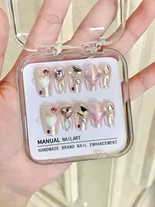 Détail de faux ongles faits main mocha avec cœurs et strass brillants en coffret