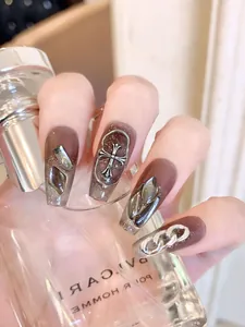 Detailed view of brown gradient press-on nails with silver gothic cross and chain accents