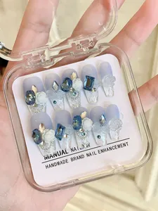 Detalle de uñas postizas hechas a mano con degradado azul y arte de rosas 3D