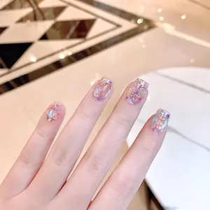 Uñas postizas artesanales aurora con lentejuelas rosa púrpura sobre fondo mármol