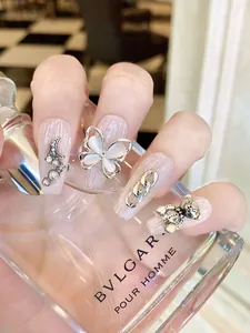 Detail of handmade press-on nails with silver butterfly, crystal bear and pearl charms