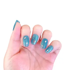 Faux ongles œil de chat bleu avec motifs étoiles pailletées et strass sur fond blanc