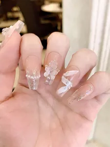 Detailed macro of pink gradient press-on nails with 3D ribbon, rose and pearl charms
