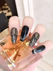 Macro shot of long coffin nails with black cat-eye finish and luxury 3D gemstones