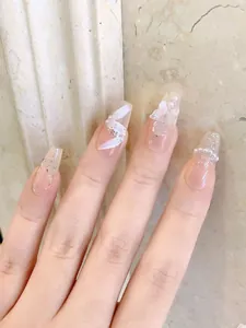 Detail of coffin-shaped press-on nails with 3D floral motifs, pearls and silver glitter