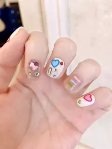 Close-up of handmade Y2K press-on nails featuring 3D pink hearts and blue patterns