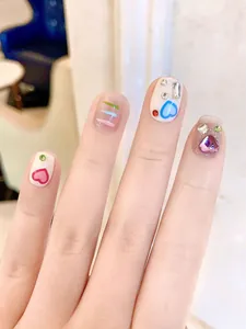 Macro shot of y2k style press-on nails featuring 3D hearts and colorful rhinestones