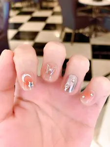 Close-up of handmade press-on nails with silver butterflies and sparkling rhinestones