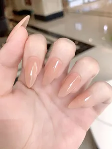 Close-up of nude pink almond press-on nails with high gloss finish on a model hand