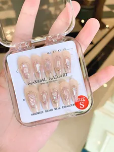 Detailed view of handmade press-on nails in champagne with gold shell and glitter details