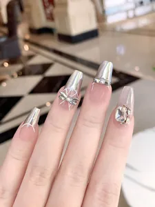 Close-up of luxury press-on nails with silver bows, pearls and sparkling rhinestones