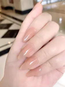 Close-up of glossy nude pink almond-shaped press-on nails with a high-shine finish