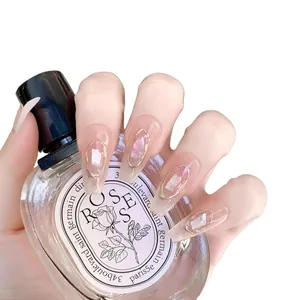 Long press-on nails with pink gradient, shell texture, and gold oval frames on fingers